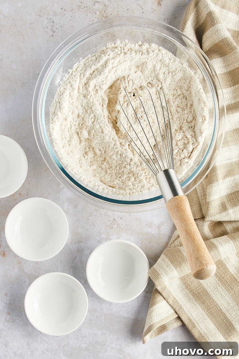 Overhead view of the dry ingredients for Gingerdoodle Cookies (flour, baking soda, ginger, cream of tartar, salt) thoroughly mixed in a glass bowl.