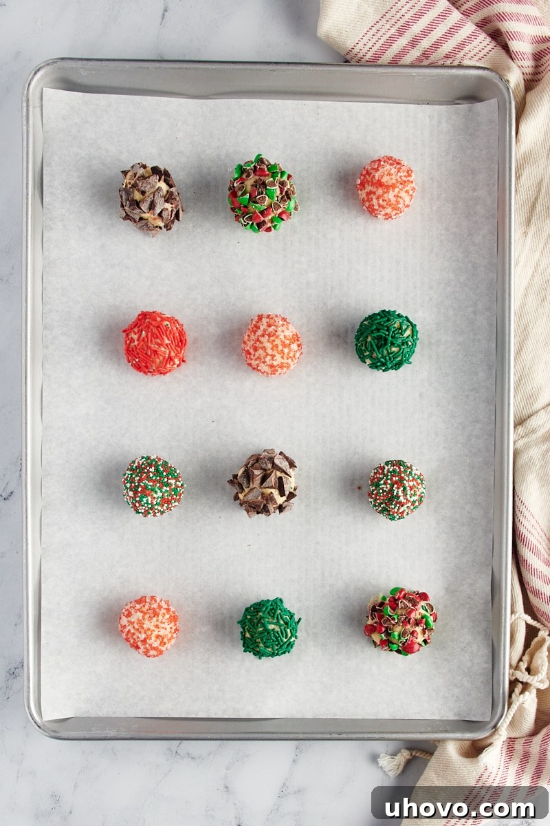 Overhead view of sugar cookie dough rolled in various toppings and placed on a parchment-lined baking sheet.