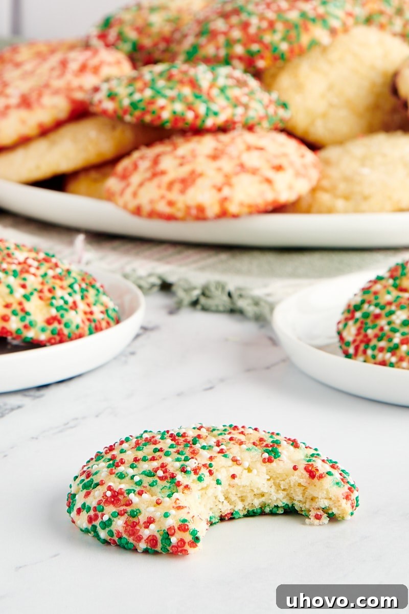 A sugar cookie with a bite missing and with more cookies in the background.