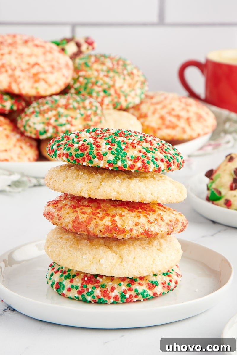 Stack of sugar cookies on a small white plate with more cookies in the background.