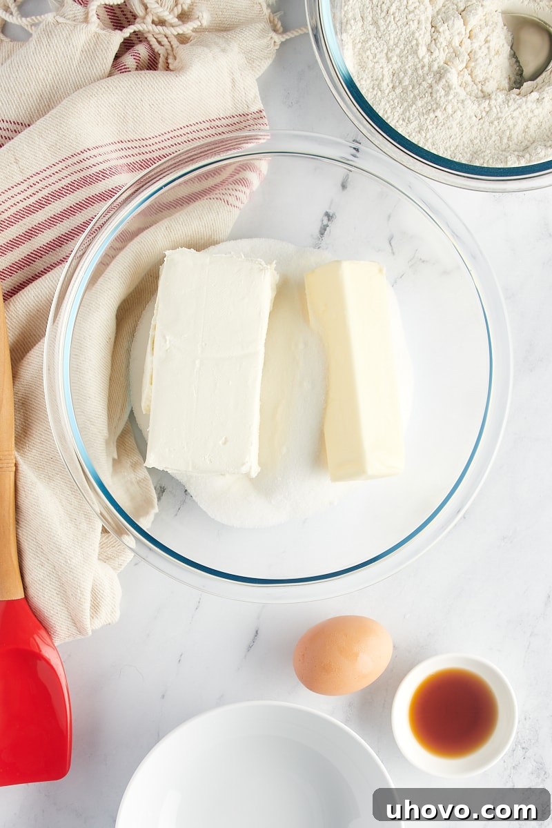 Overhead view of butter, cream cheese, and sugar in a glass mixing bowl.