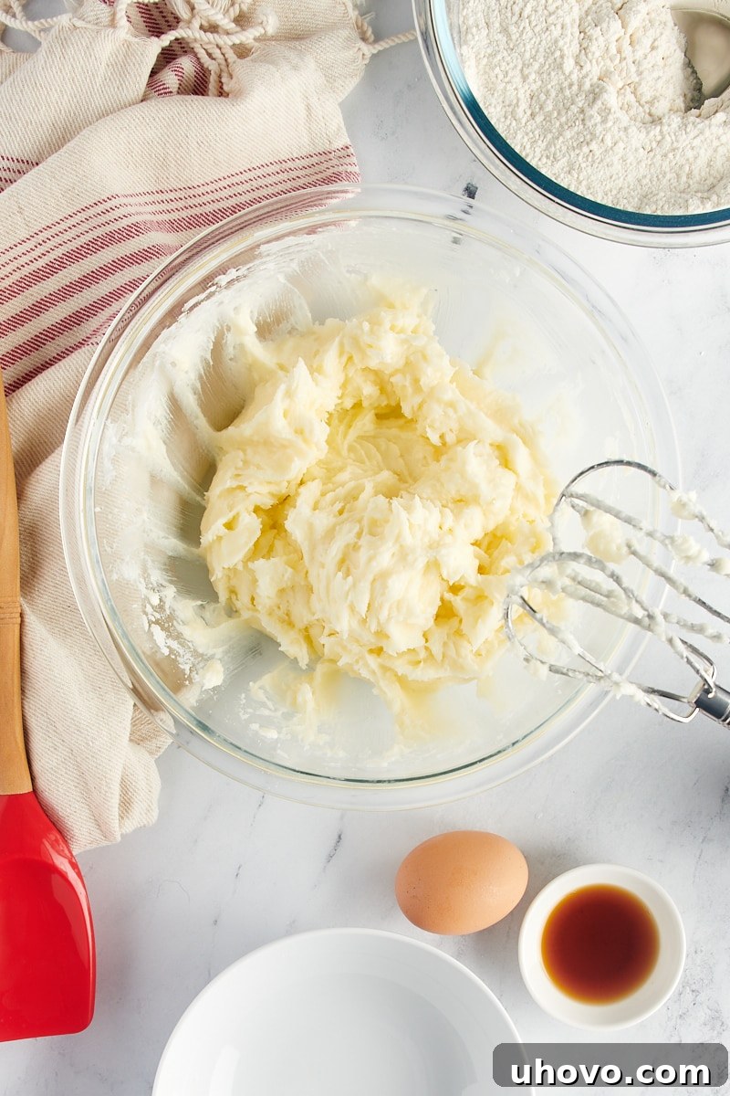 Overhead view of creamed butter, cream cheese, and sugar in a glass mixing bowl.