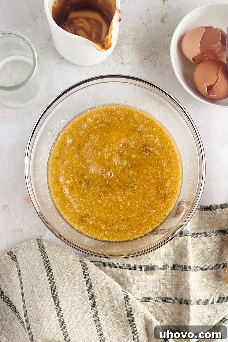 An overhead view of the thoroughly mixed wet ingredients for gingerbread muffins, a smooth, homogenous blend of eggs, butter, molasses, and milk.