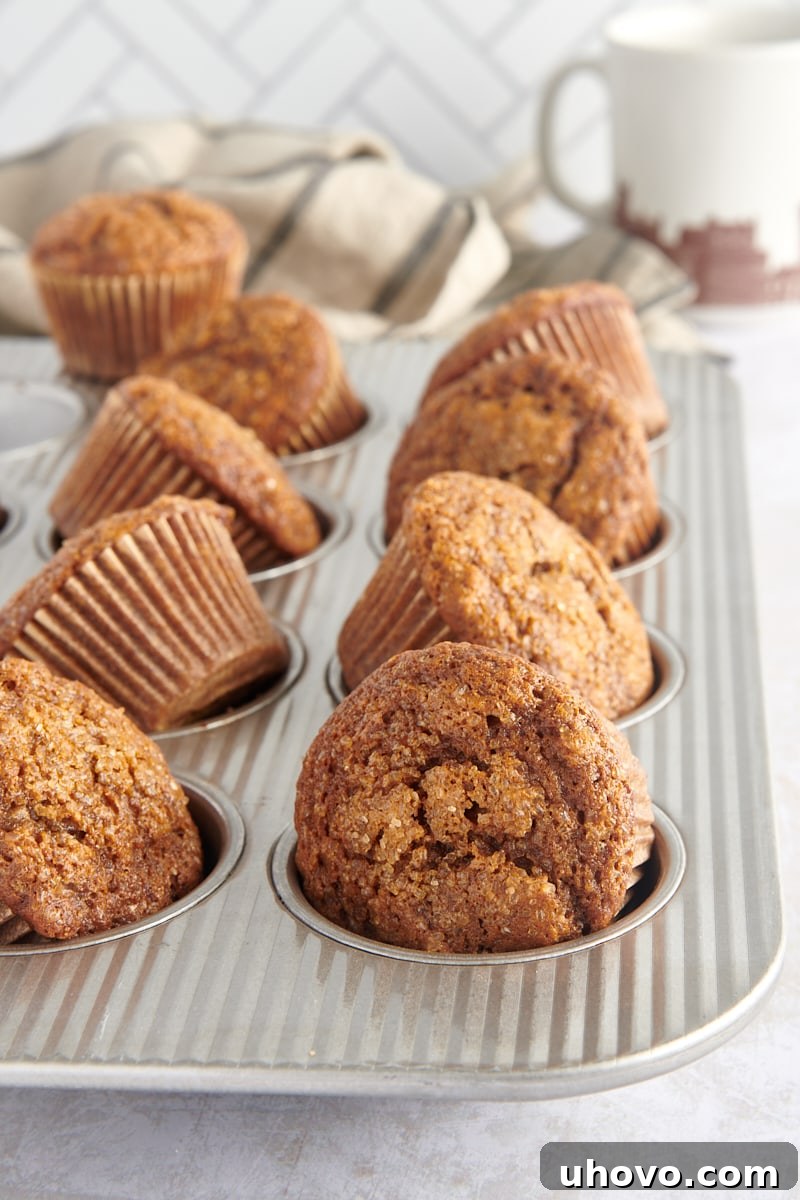 Several fragrant gingerbread muffins partially lifted from the muffin pan, showcasing their perfect shape and golden-brown crust.