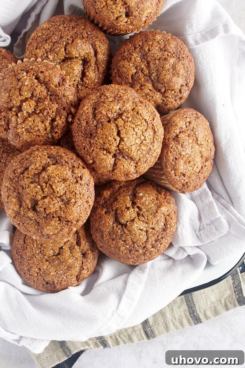 An inviting overhead view of warm, golden-brown gingerbread muffins nestled charmingly in a white tray lined with a clean towel.