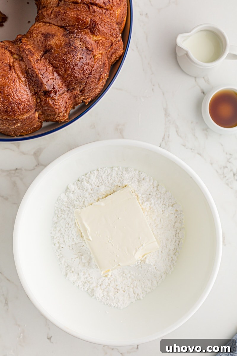 overhead view of cream cheese and confectioners' sugar in a white mixing bowl