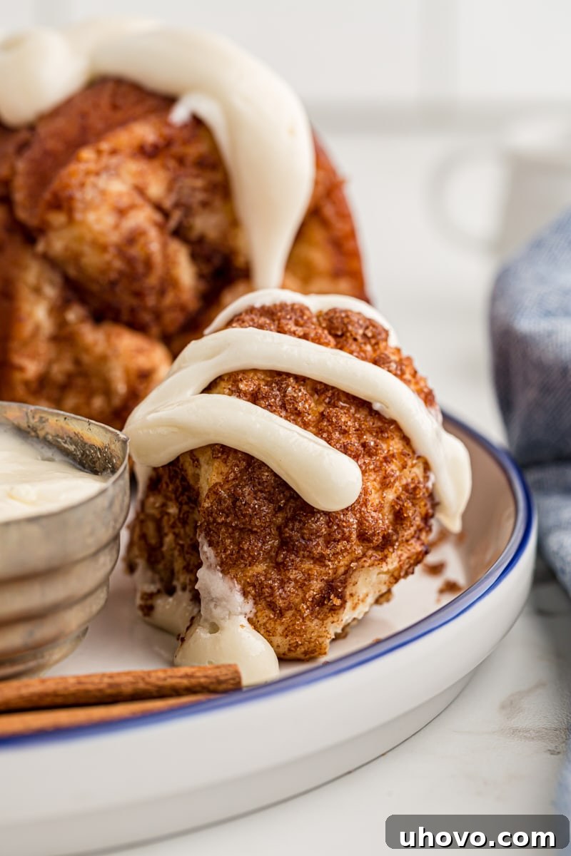 a piece of Monkey Bread drizzled with cream cheese icing with more bread in the background