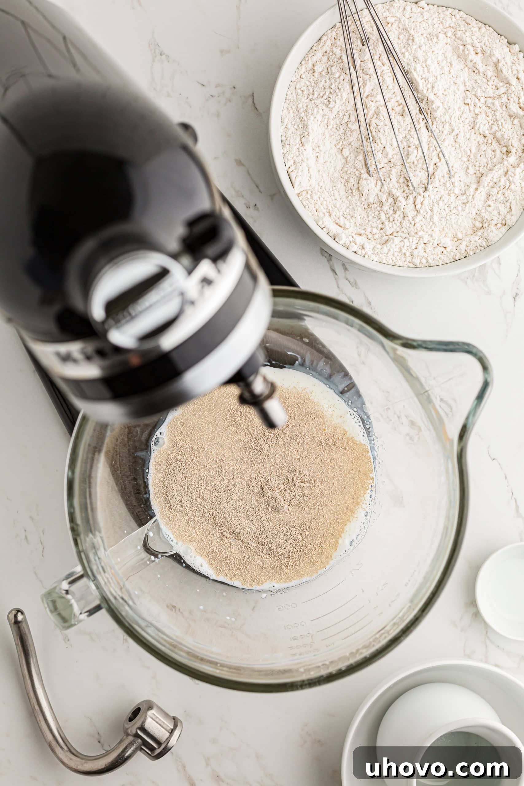 overhead view of milk, water, butter, sugar, and yeast in the bowl of a stand mixer