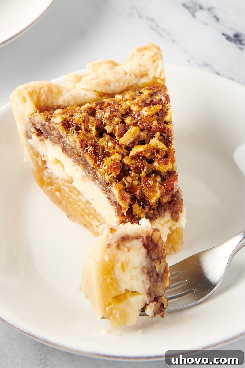 A slice of Pecan Cheesecake Pie with a bite taken out, resting on a fork.