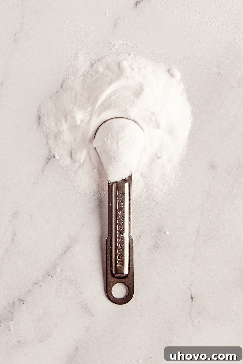 baking soda in a measuring spoon and in a pile on a marble surface