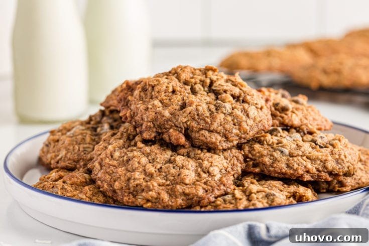 Stack of cowboy cookies on plate with bottles of milk in background