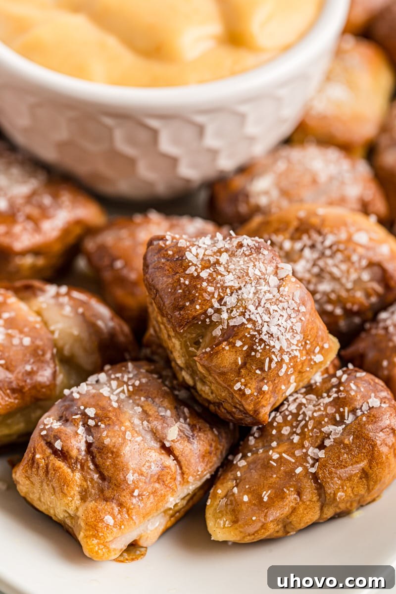 Golden brown homemade pretzel bites served on a white plate with a side bowl of creamy beer cheese dip, ready for sharing.
