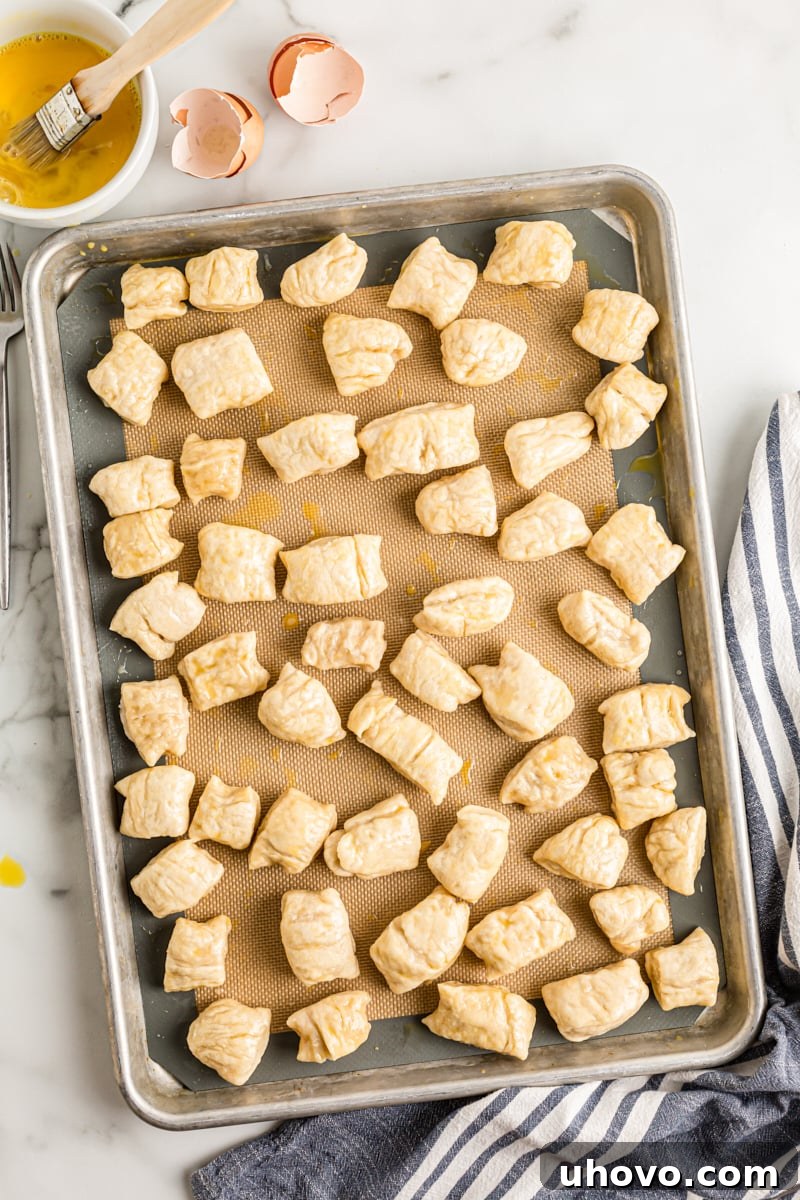 Pretzel bites on a baking sheet, glistening after being brushed with an egg wash, preparing them for a beautiful golden-brown crust.