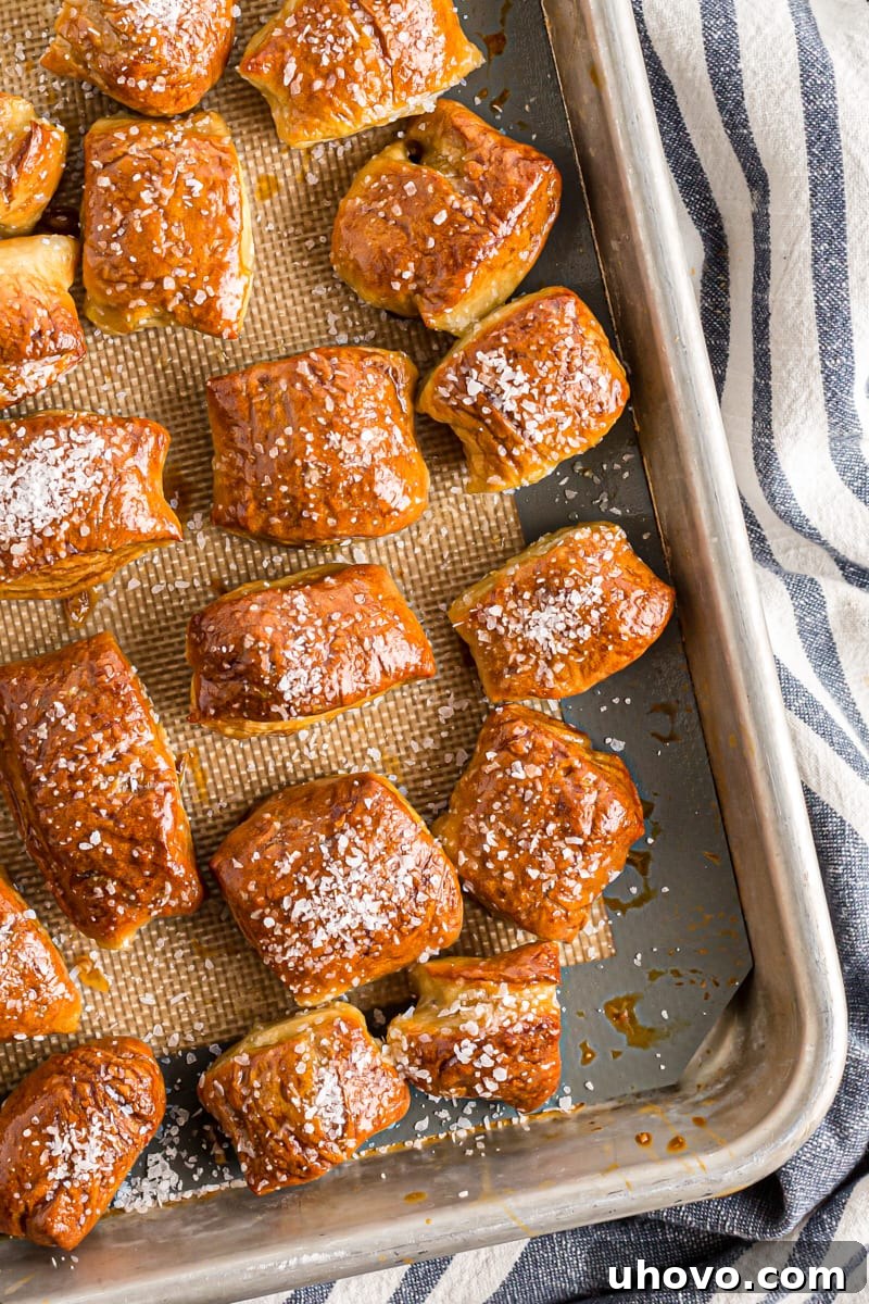 A freshly baked batch of perfect pretzel bites, glistening with butter and sprinkled with coarse salt, resting on a baking sheet.