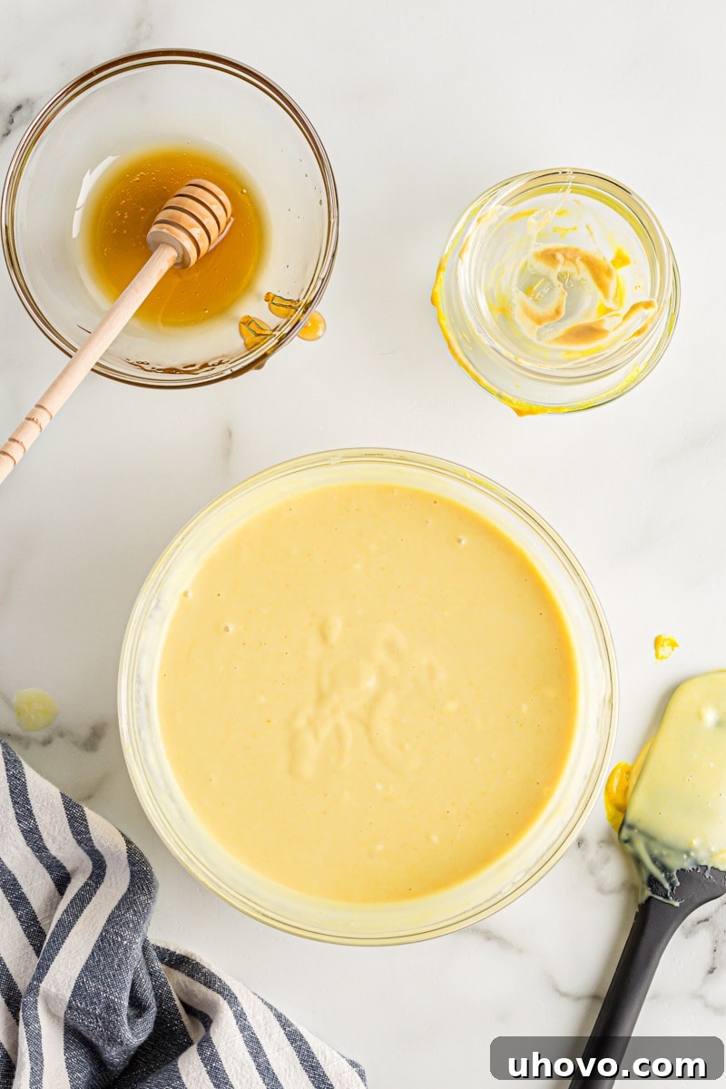 A smooth, creamy honey mustard dipping sauce in a glass mixing bowl, perfectly blended and ready for chilling.