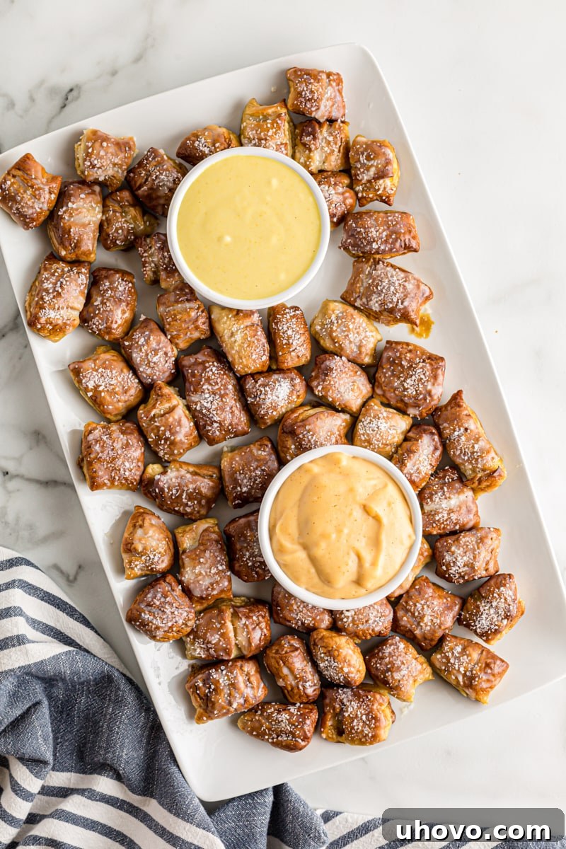 A festive platter of golden homemade pretzel bites, artfully arranged and served with bowls of creamy honey mustard and rich beer cheese dips, ideal for any gathering.