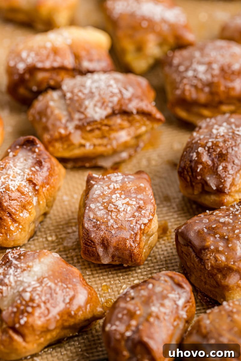 A batch of golden pretzel bites cooling on a baking sheet lined with a silicone mat, showcasing their perfect texture and even bake.