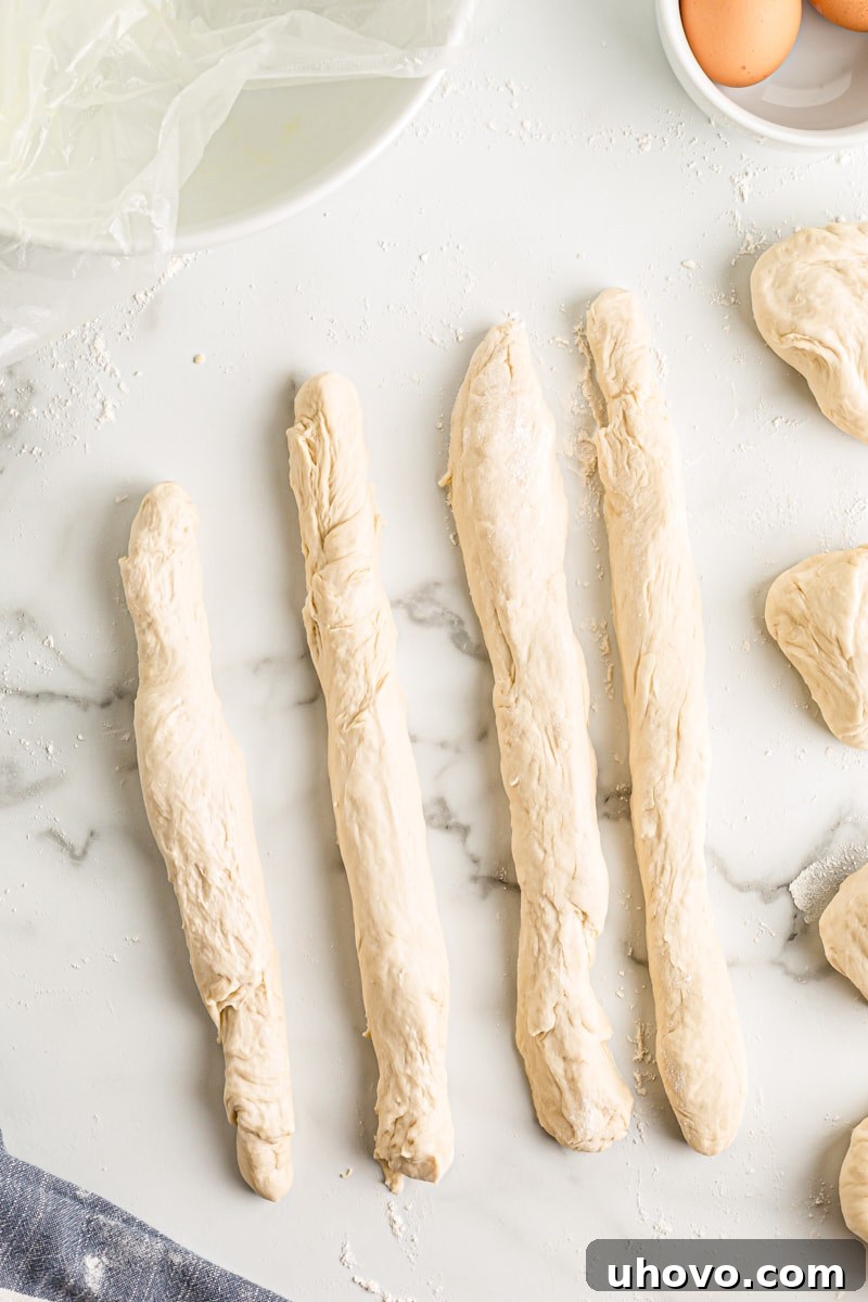 Pretzel dough expertly rolled into long, thin ropes, ready for cutting into bite-sized pieces.