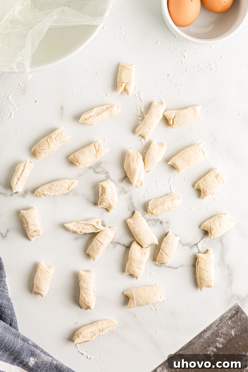 Precisely cut 1-inch pieces of pretzel dough, arranged neatly and ready for the baking soda bath.
