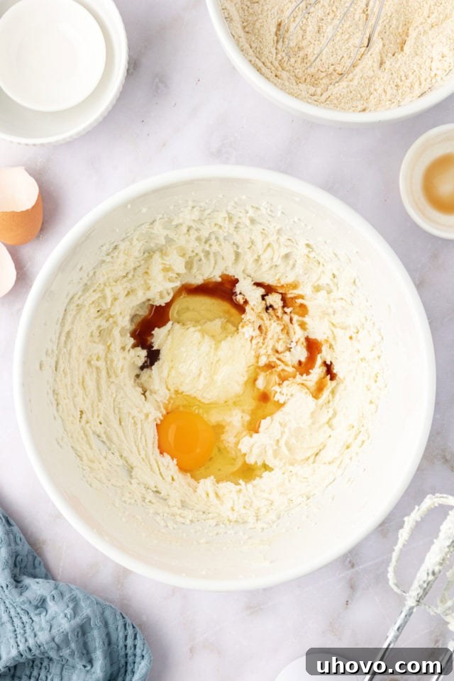 overhead view of an egg and vanilla extract being added to the creamed butter and sugar mixture