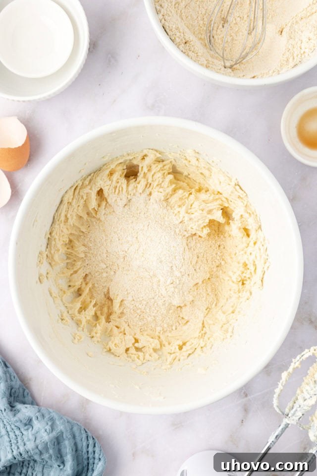 overhead view of the combined dry ingredients being gradually added to the wet ingredients in a mixing bowl