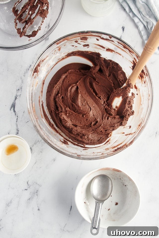 overhead view of chocolate buttercream frosting in a glass mixing bowl