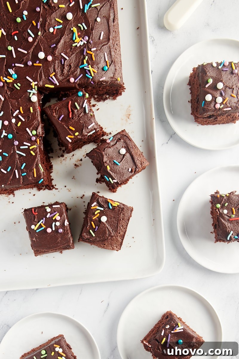 overhead view of partially sliced Chocolate Sheet Cake on a serving tray and on white plates