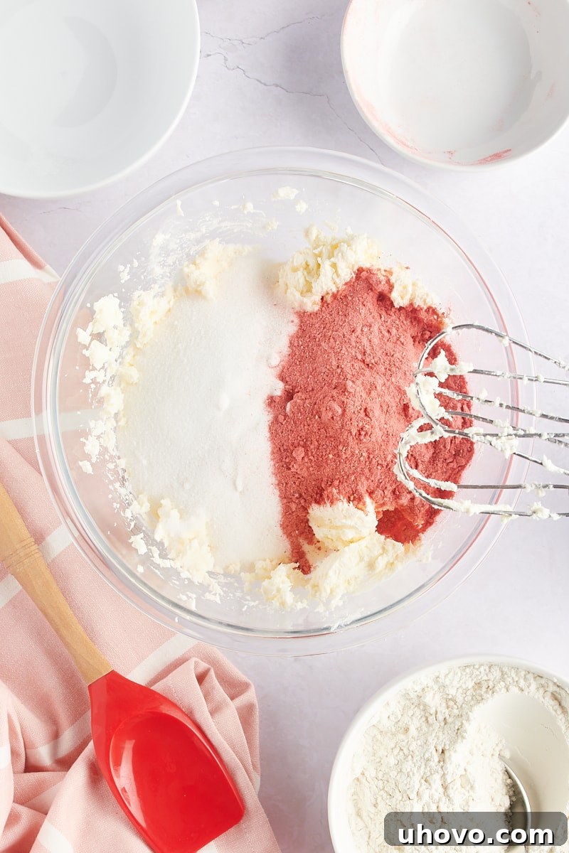 overhead view of sugar and freeze-dried strawberries added to creamed butter and cream cheese