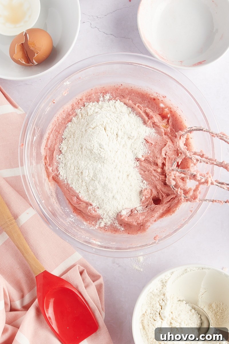 overhead view of dry ingredients added to strawberry cookie dough