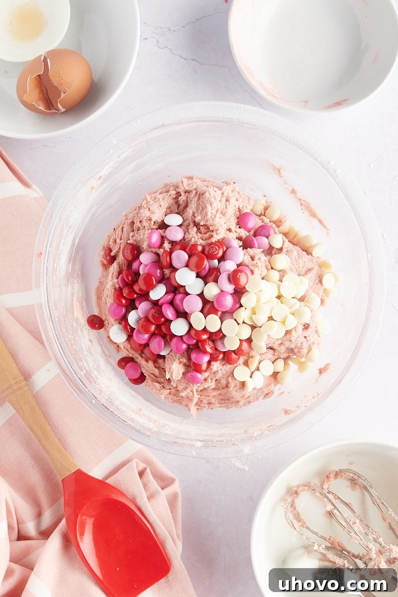 overhead view of M&Ms and white chocolate chips added to strawberry cookie dough