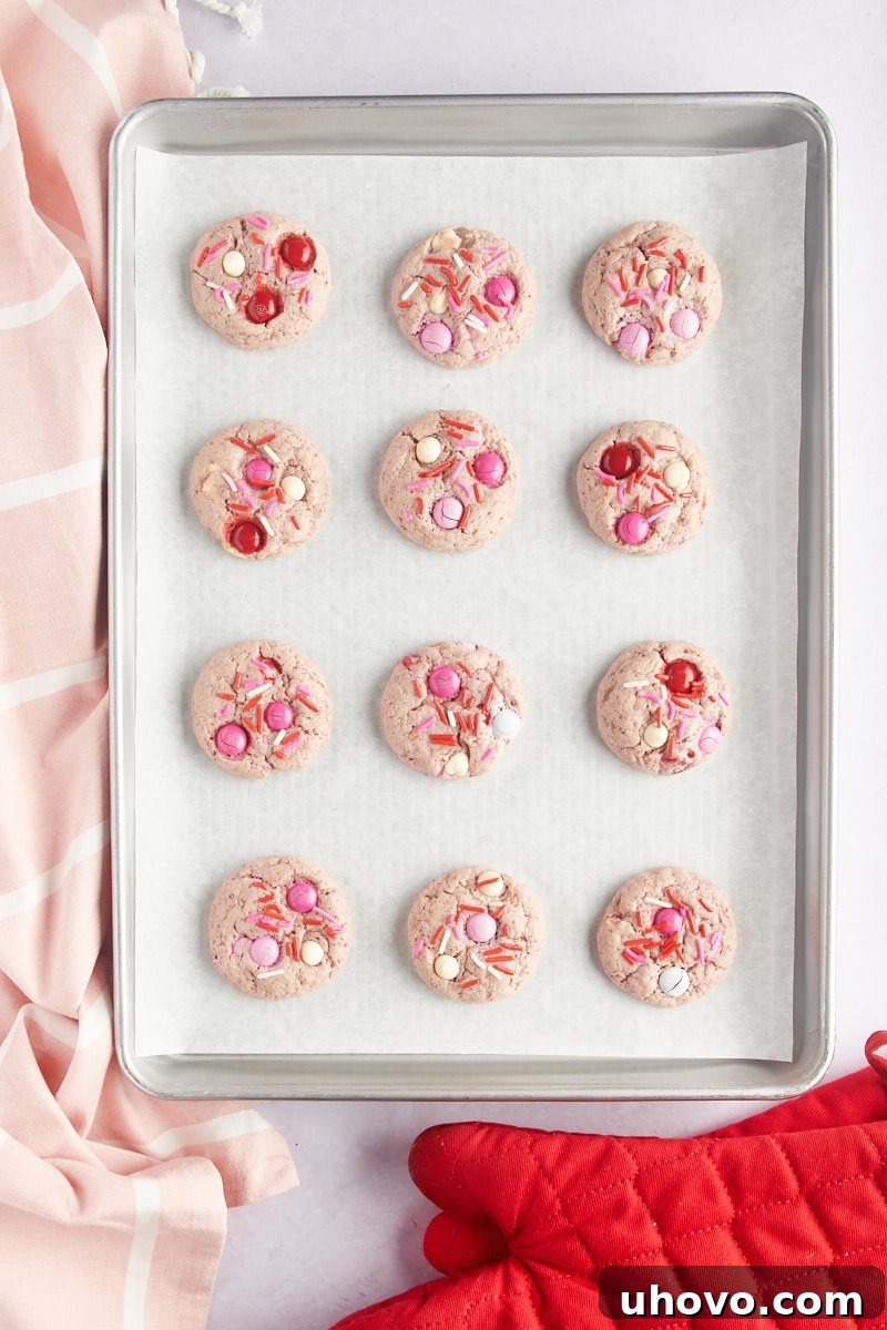 overhead view of freshly baked Strawberry M&M Cookies on a parchment-lined baking sheet
