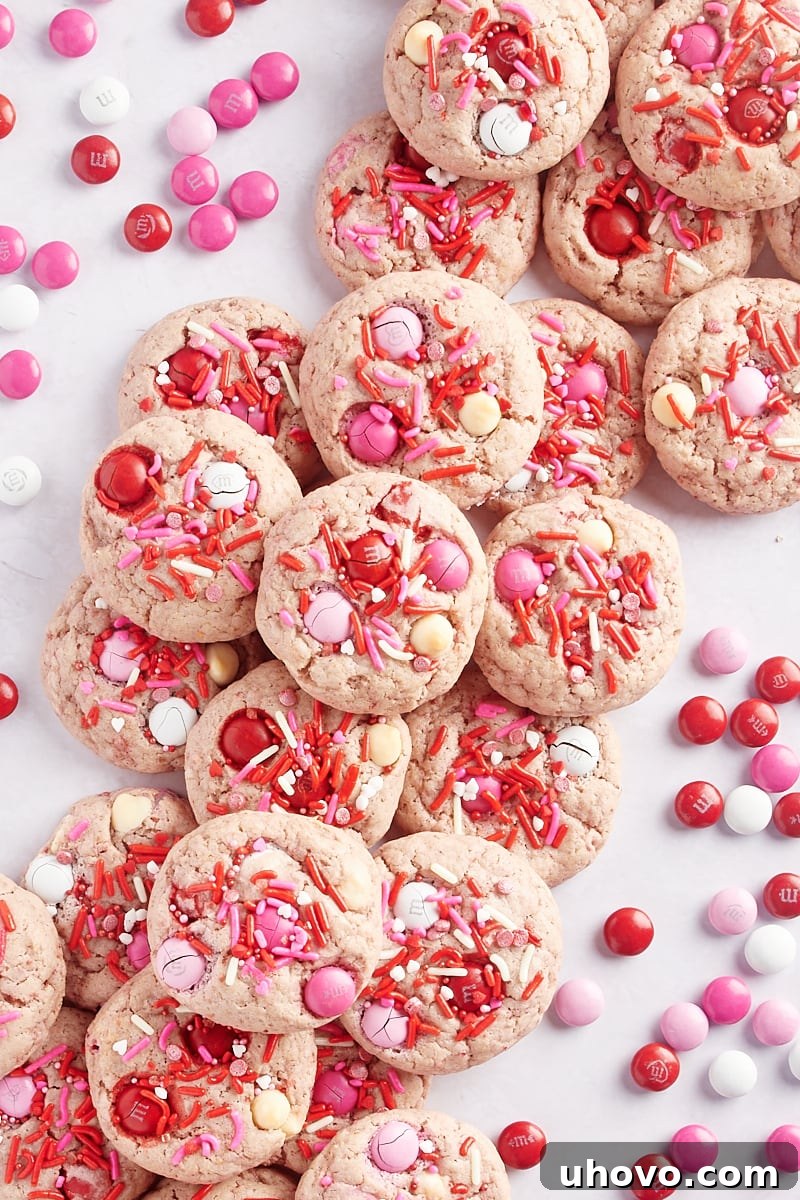 overhead view of Strawberry M&M Cookies on a marble surface with red, pink, and white M&Ms scattered around the cookies