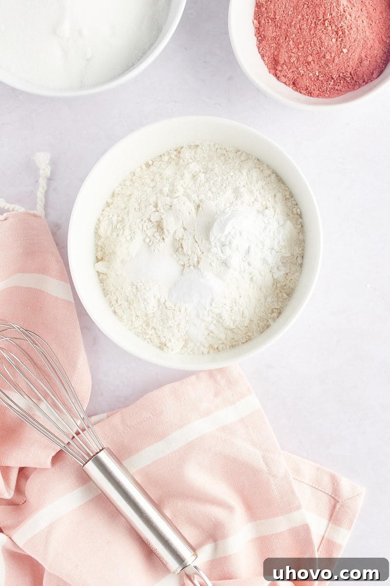 overhead view of flour, baking powder, baking soda, and salt in a white mixing bowl