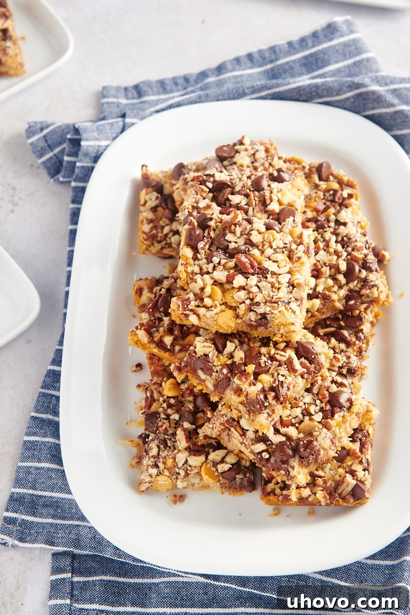 Seven layer bars stacked on white platter, showcasing their delightful layers