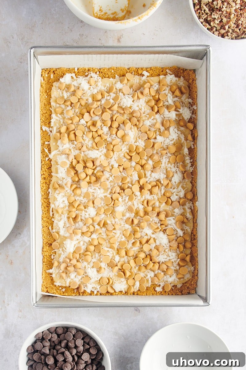 Overhead view of seven layer bars after adding coconut and butterscotch chips to the condensed milk layer