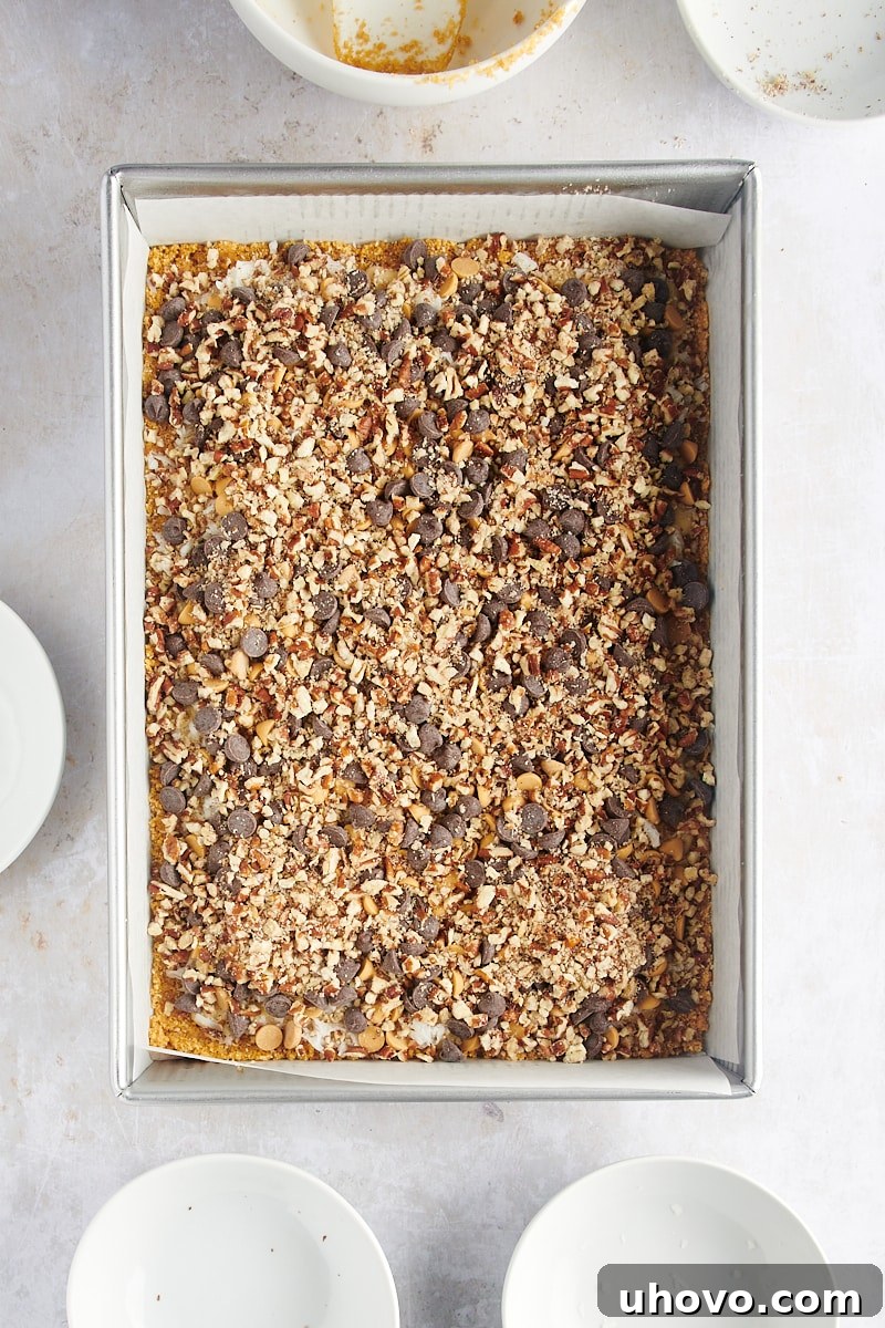 Unbaked pan of seven layer bars with all toppings evenly distributed