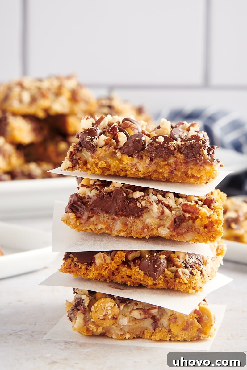 Stack of 4 seven layer bars with parchment paper between each, showing off their perfectly baked layers