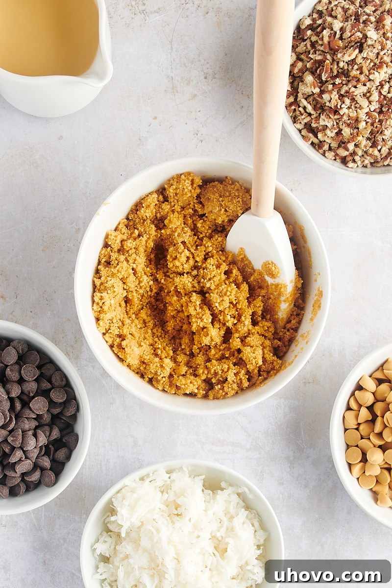 Overhead view of graham crust mixture in small bowl with rubber spatula, ready to be pressed