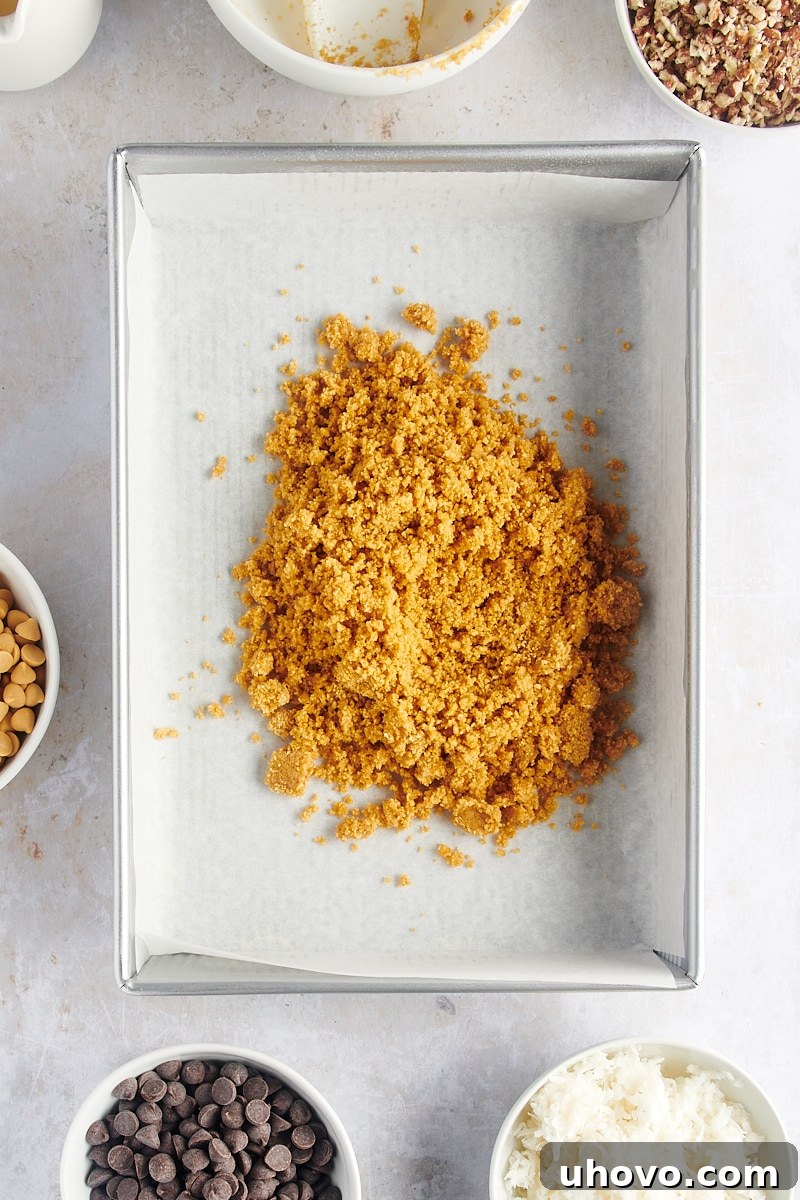 Overhead view of crust mixture poured into parchment-lined pan, ready for pressing