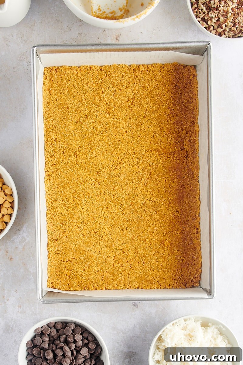 Graham cracker crust evenly pressed into a baking pan, forming the base for seven layer bars