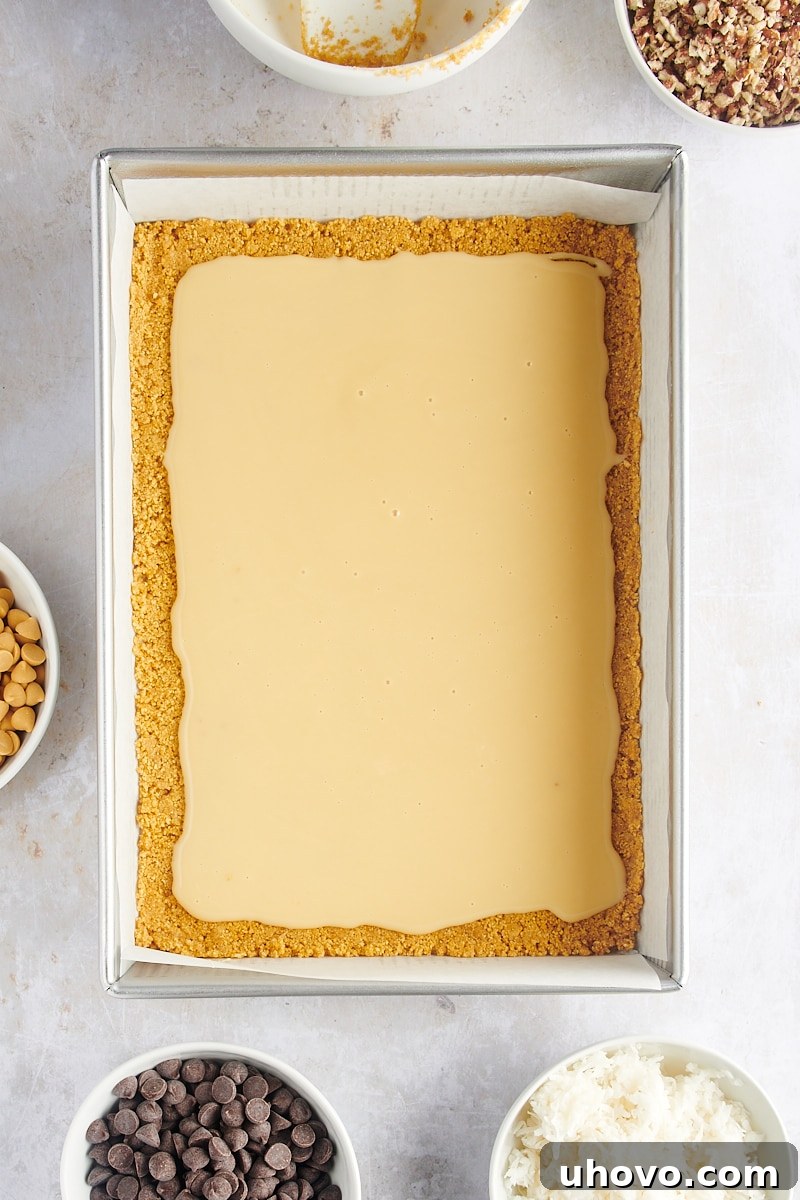 Overhead view of seven layer bars after condensed milk has been spread over the crust