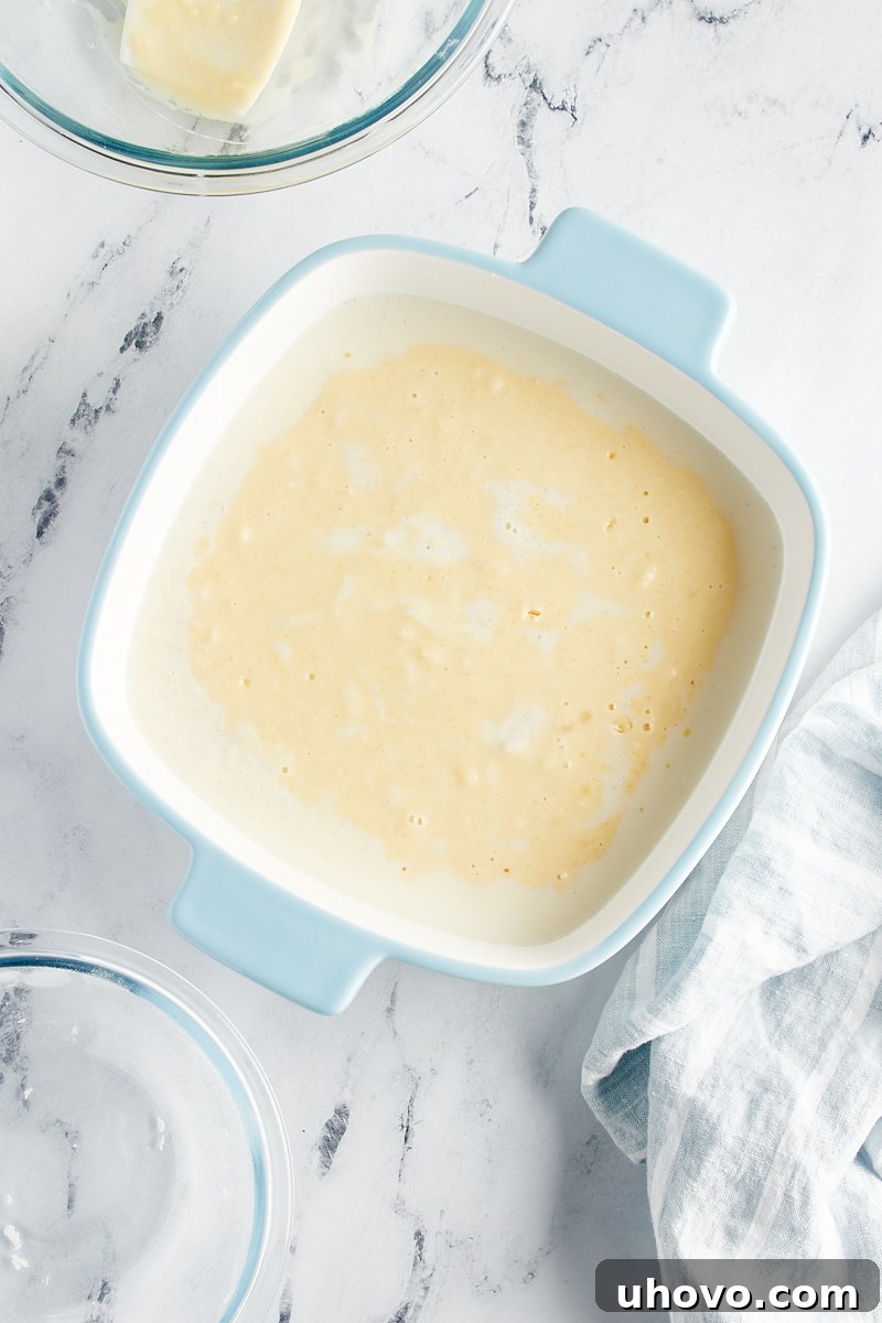 The fully assembled Vanilla Pudding Cake, with the cake batter spooned over the pudding layer in the baking pan, poised to go into the oven.