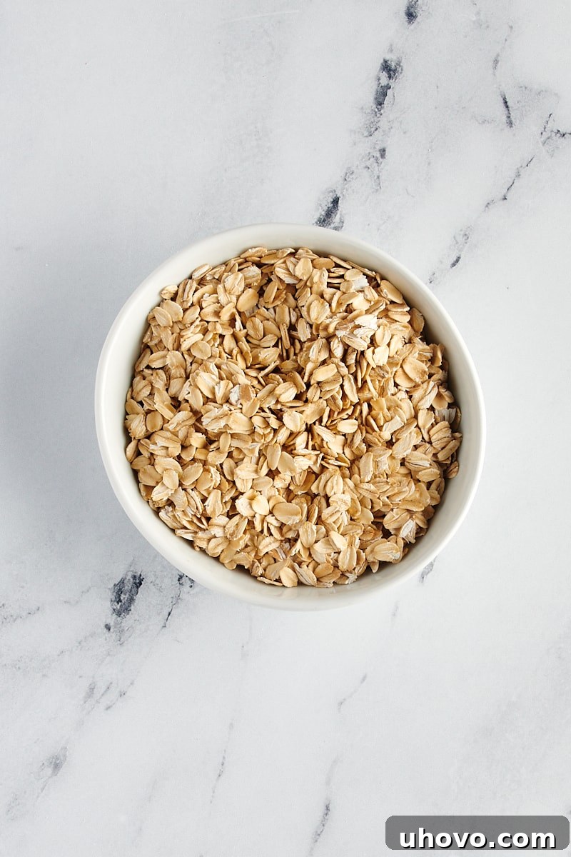 overhead view of rolled oats in a white bowl on a marble surface