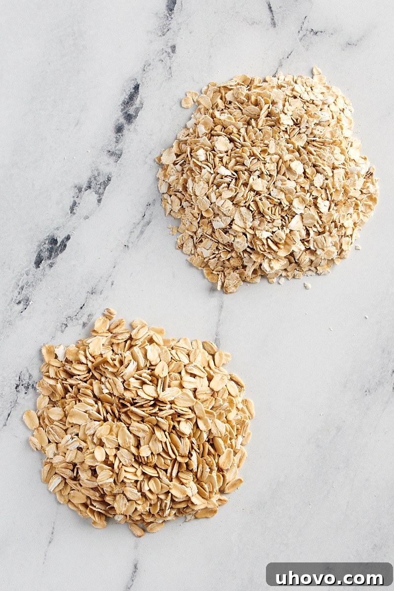 side by side piles of rolled oats and quick oats on a marble surface