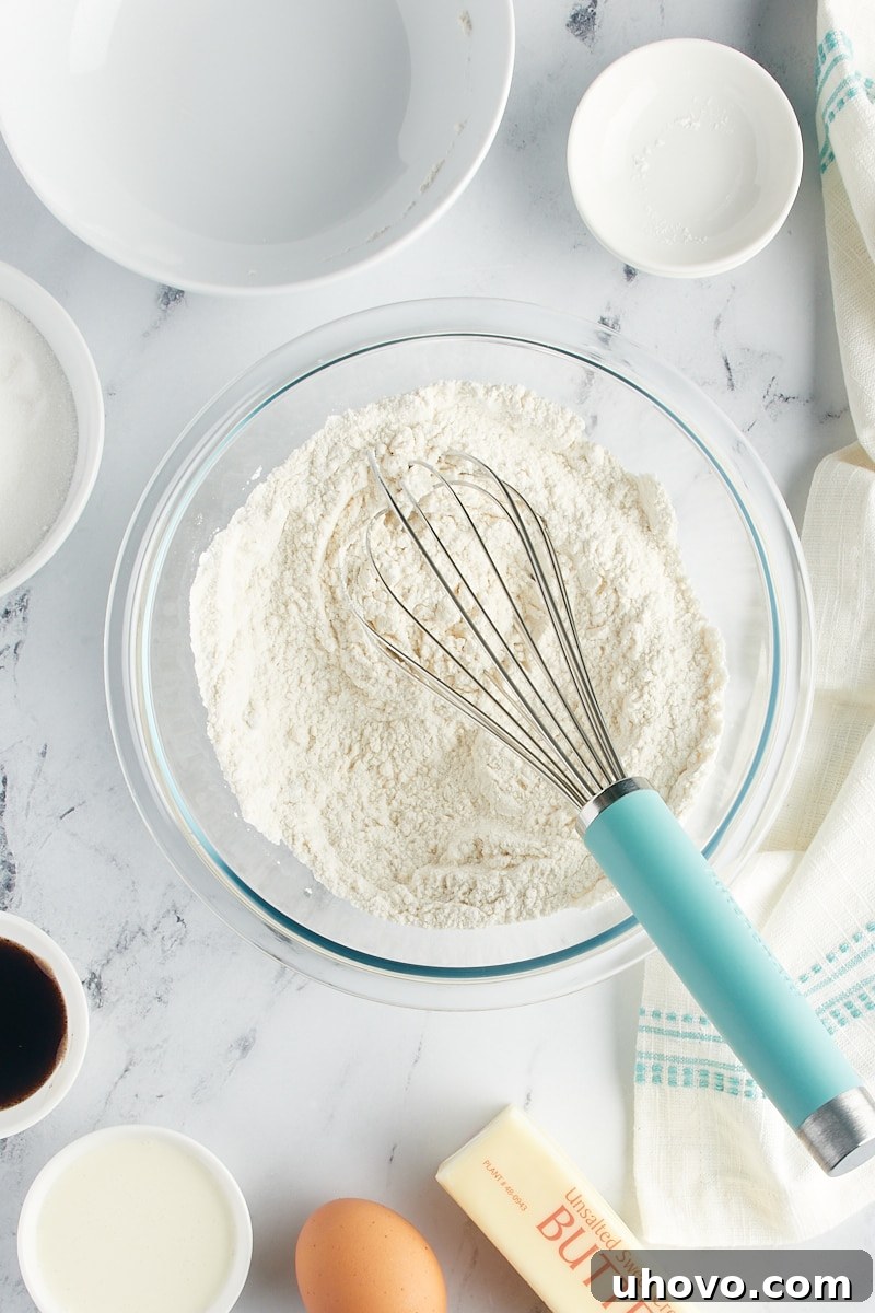 Overhead view of dry cookie ingredients with a whisk in a mixing bowl.