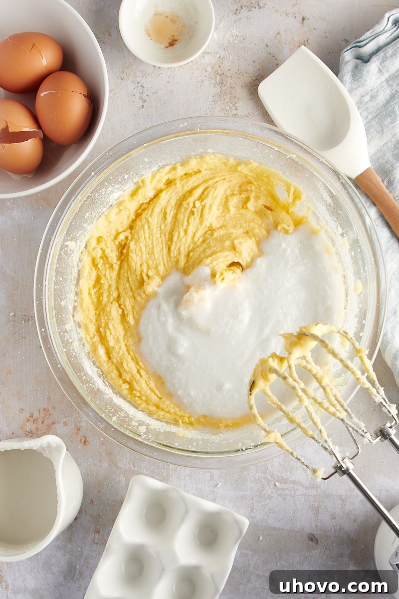 overhead view of coconut milk being added to the cake batter after dry ingredients
