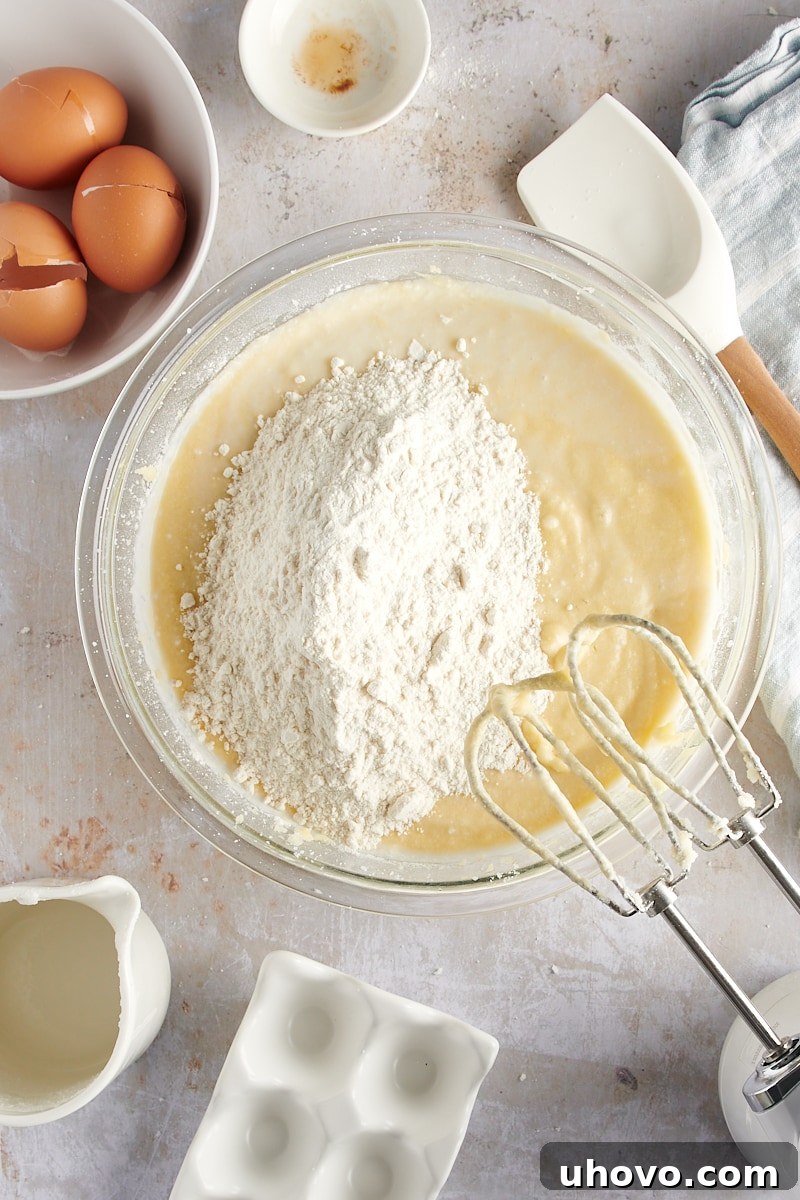 overhead view of the final portion of flour being added to the cake batter