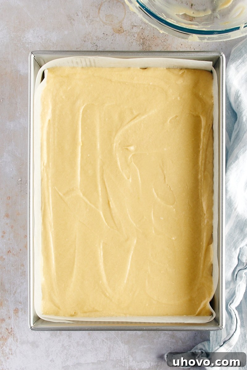 overhead view of coconut cake batter spread evenly in a 9x13 baking pan, ready for the oven