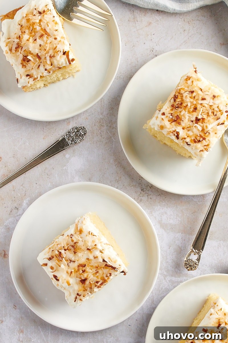 overhead view of slices of Coconut Sheet Cake on white plates, ready for serving