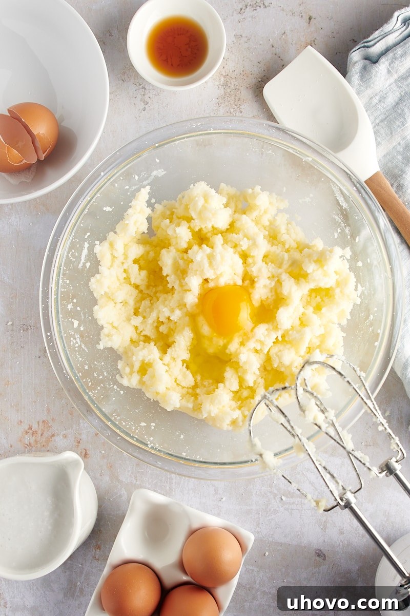 overhead view of one egg just added to the creamed butter and sugar mixture in a glass bowl